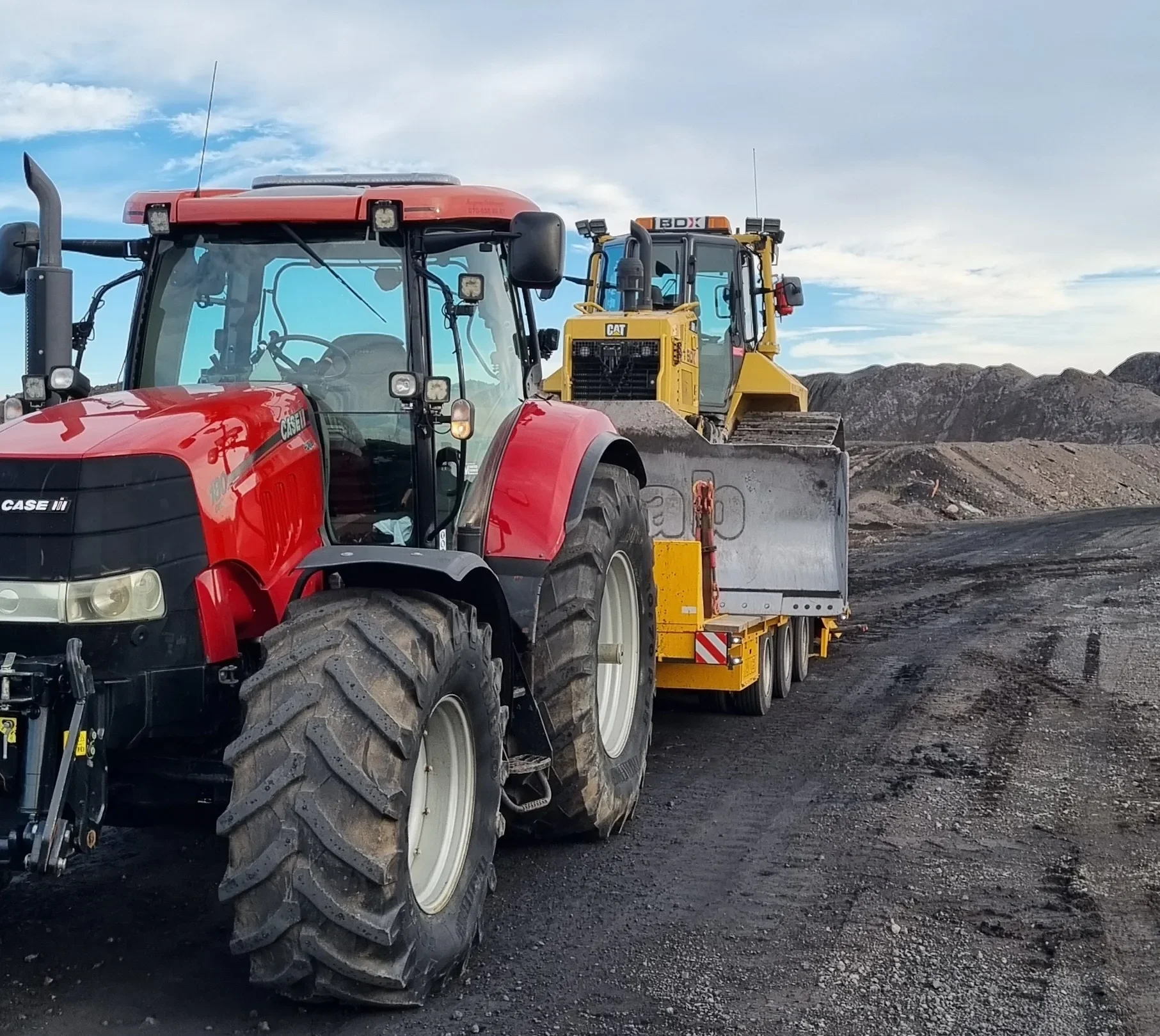 Tung transport – Case-traktor med CAT-maskin på industrigata